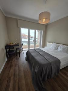 a bedroom with a bed and a table and a window at Mãe Maria House Guest House in Vila Chã