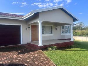 a white house with a gate and a garage at Modern , Spotless Townhouse in Quiet Estate - Pietermaritzburg in Pietermaritzburg