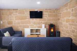 a living room with a couch and a tv on a brick wall at Refugio dos Coviais in Guarda