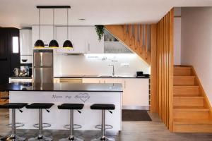 a kitchen with a counter with bar stools and a staircase at Refugio dos Coviais in Guarda