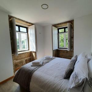 a bedroom with a large bed with two windows at Refugio dos Coviais in Guarda +76 photos