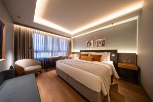 a hotel room with a large bed and a chair at Laghetto Stilo Aeroporto in Porto Alegre