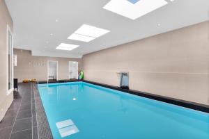 a large swimming pool with blue water in a building at Villa Stavanger 5 bedrooms 5 bathrooms and large swimming pool in Stavanger