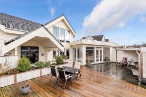 a house with a deck with a table and chairs at Villa Stavanger 5 bedrooms 5 bathrooms and large swimming pool in Stavanger
