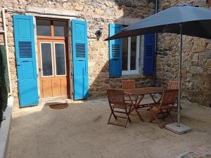 a table with two chairs and an umbrella in front of a building at Appartement avec terrasse 53m2 in Saint-Martin-de-Valamas