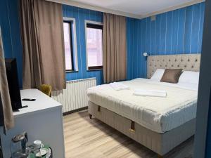 a bedroom with a bed and a blue wall at Goldel Resort in Delčevo