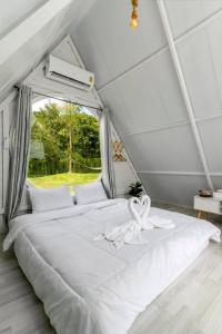 a white bed in a room with a window at Phunapat camping in Cha Am
