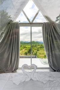 a bedroom with two heart sculptures on a bed in front of a window at Phunapat camping in Cha Am