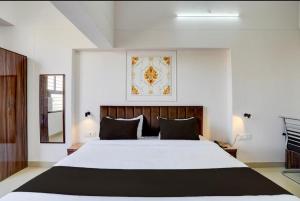 a bedroom with a large white bed with black pillows at Hotel Vijai Square in Prayagraj