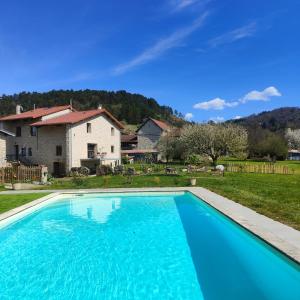 a large blue swimming pool in front of a house at A l'ombre des vignes, chambres d'hôtes 3 épis avec piscine in Poncin