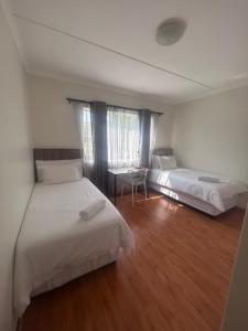a bedroom with two beds and a table in it at Modern , Spotless Townhouse in Quiet Estate - Pietermaritzburg in Pietermaritzburg