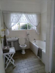 a bathroom with a tub and a toilet and a sink at Eskulaap Hotel in Polokwane +12 photos