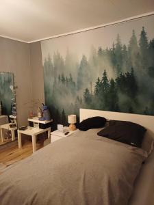 a bedroom with a large painting of trees on the wall at Eifelsteigzimmer Bruderherz in Gerolstein
