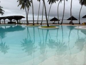 a large swimming pool next to a beach with palm trees at Antonio Beach in Uroa