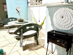 a table and a chair next to a piano at Solar Boutique Residence in Pouso Alegre
