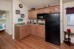 a kitchen with a black refrigerator and wooden cabinets at Sun Outdoors Central Coast Wine Country in Paso Robles