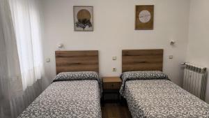 two beds in a room with white walls at Hostal Angelines in Madrid