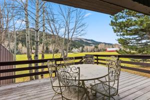 a table and chairs on a deck with a view of a field at Mountain View Condo - Hot Tub Fireplace in Avon