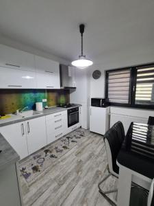 a kitchen with white cabinets and a sink and a table at Romanescu Park Apartament in Craiova