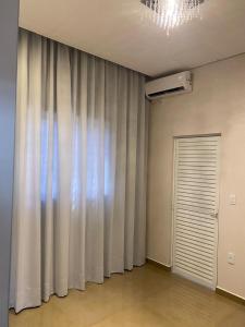 a room with a white curtain and a door at Casa linda e nova, 01 suíte, 02 camas - até 03 pessoas in Chapecó