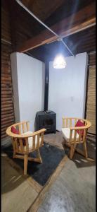 two wooden chairs in a room with a stove at cabaña del teyu in Puerto Cazador