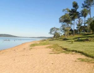 a sandy beach with trees and the water at cabaña del teyu in Puerto Cazador