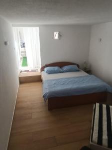 a bedroom with a bed with blue sheets and a window at River & Garden Apartment in Trebinje