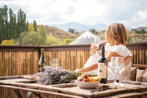 a woman sitting on a balcony holding a glass of wine at Bali Andino Vilas in Ciudad Lujan de Cuyo