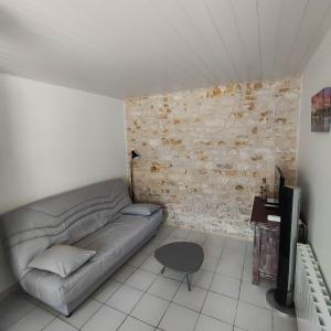 a living room with a couch and a brick wall at La Flottille, La Cotinière in La Cotinière
