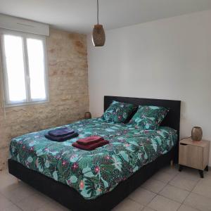 a bedroom with a bed with a green comforter at La Flottille, La Cotinière in La Cotinière