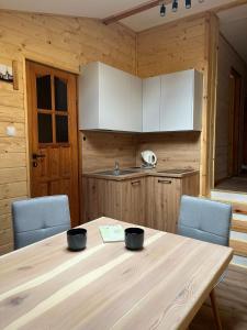 a kitchen with a wooden table and two blue chairs at Nad Stawami - studio in Białowieża