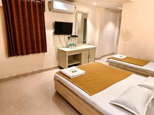 a bedroom with two beds and a television in it at SD Blueberry Hotel in Shirdi