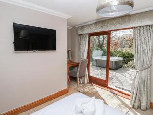 a bedroom with a tv on the wall and a tub at Oak Tree Cottage - Gower in Swansea