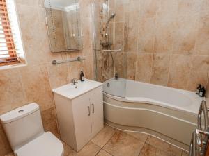 a bathroom with a toilet and a tub and a sink at Oak Tree Cottage - Gower in Swansea +44 photos