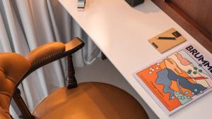 a desk with a chair next to a table with a book at Ruby Stella Hotel London by IHG in London +69 photos