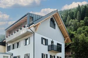 a large white building with a balcony and trees at Alp Tirol Home in Pellizzano