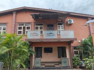 ein rosa Haus mit Balkon und Palmen in der Unterkunft Eliteclassy in Iju