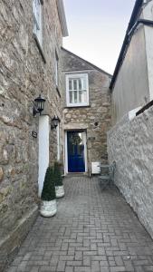 a stone building with a blue door and two bushes at Minster Panorama & Minster Vista - - UNBROKEN BEACHFRONT VIEWS - - TWO STUNNING GEORGIAN HOUSES THAT CONNECT - - PRIVATE PARKING - - Beautifully Refurbished MARCH 2026 in St Ives