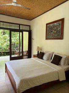 a bedroom with a large bed and a balcony at Raka Rai Bungalows in Ubud +91 photos