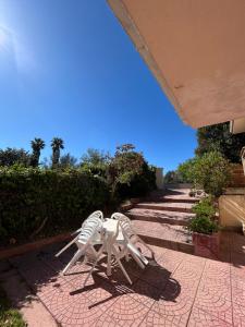 Zwei weiße Gartenstühle stehen auf einer Terrasse in der Unterkunft Parco Delle Valli in Sassari