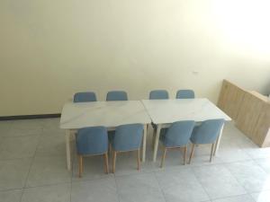 a conference room with a white table and blue chairs at Travel Island B&B in Beigan