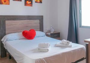 a red heart pillow sitting on a bed with towels at Apartalux Paraíso Azul in Barbate