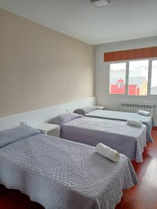 a hotel room with three beds and two windows at dpCristal Sarria Centro in Sarria