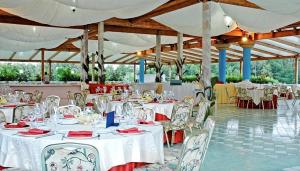 a banquet hall with white tables and chairs and white umbrellas at Villaggio Giardini D'Oriente in Nova Siri Marina