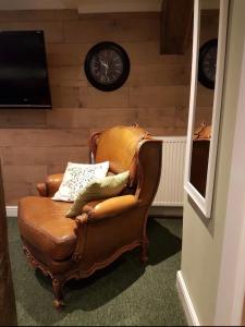 a brown leather chair in a room with a clock on the wall at The Kings Arms Pub in Stratton on the Fosse