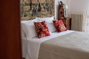 a white bed with two red pillows on it at Villa dei Domenicani in Copertino