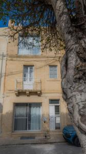 a tan building with a balcony and a tree at Sea Balcony House in Senglea
