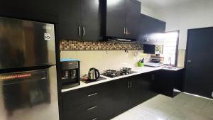 a kitchen with black cabinets and a stove top oven at Lin Homestay in Lahad Datu