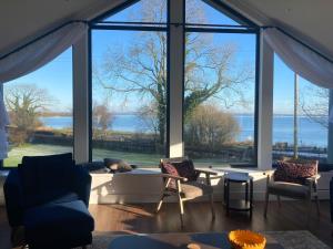 a living room with large windows and a couch and chairs at Lough View Lodge in Ballyronan