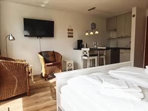 a living room with a bed and a kitchen with a tv at Strand Sand Sylt in Westerland